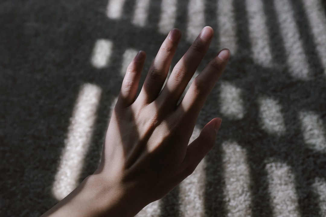A hand reaching toward light filtering through shadows